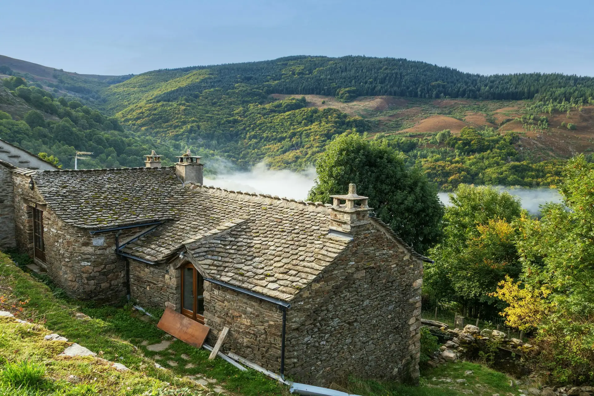 Maison en pierre et lauzes au-dessus d’une vallée des Cévennes